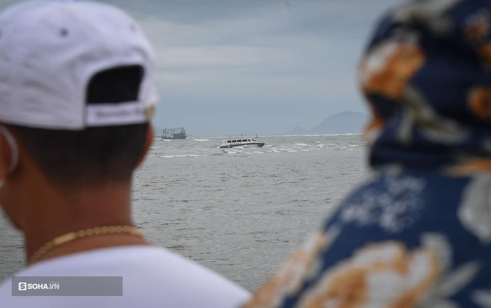 Rất đông người dân Hội An theo dõi vụ việc, phía xa là chiếc ca nô gặp nạn đang trôi nổi trên biển.