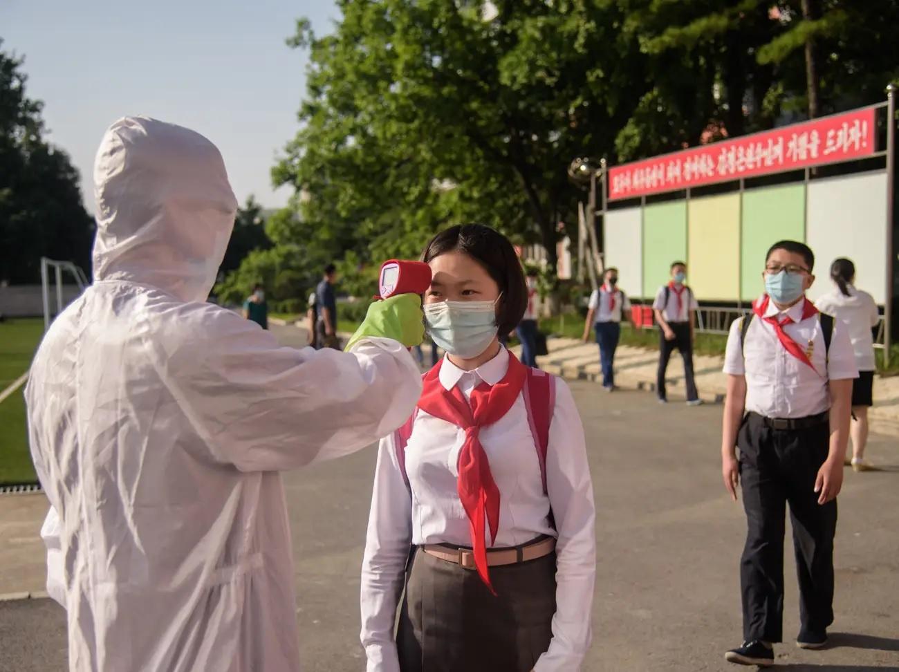 Đo nhiệt độ cho học sinh trước trường Trung học Bình Nhưỡng Số 1, ngày 22/6/2021. Ảnh: AFP.