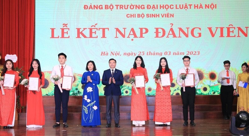 Phó Bí thư Thường trực Thành ủy Hà Nội Nguyễn Thị Tuyến và Chủ tịch Hội đồng Trường Đại học Luật Hà Nội Chu Mạnh Hùng trao quyết định và tặng hoa chúc mừng các tân đảng viên