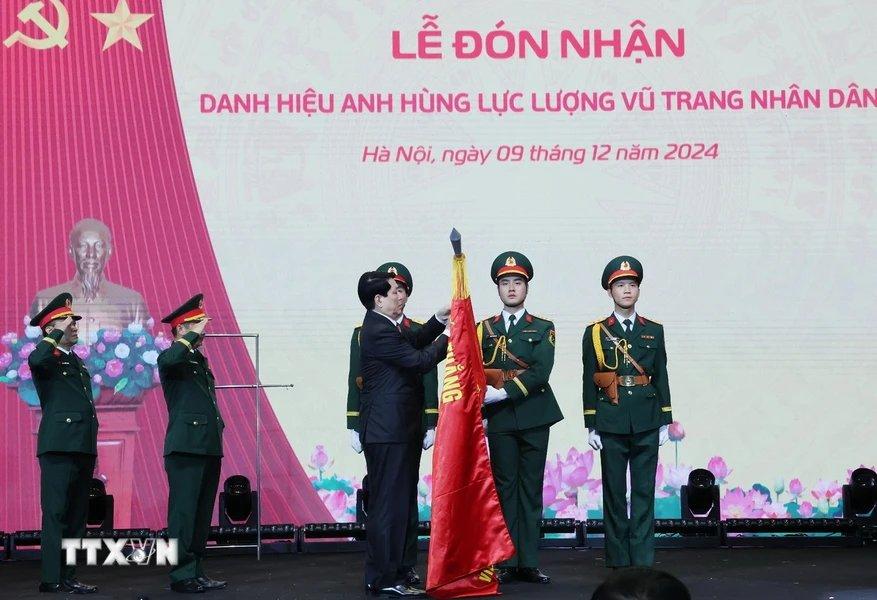 Chủ tịch nước Lương Cường gắn huy hiệu Anh hùng Lực lượng vũ trang nhân dân lên lá cờ truyền thống Viện Hàng không Vũ trụ Viettel. Ảnh: Lâm Khánh/TTXVN