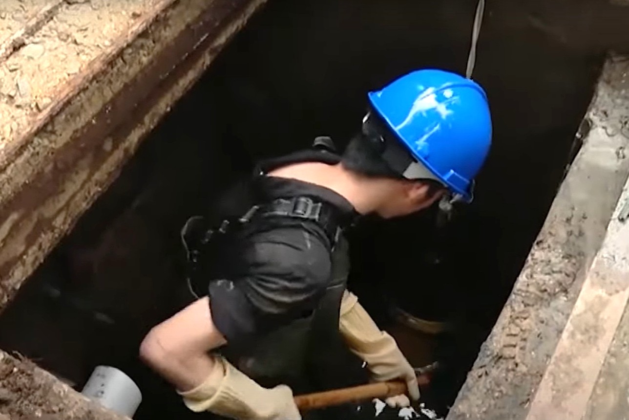 Công nhân xuống cống thoát để thực hiện công việc nạo vét. Ảnh: Q.Hằng