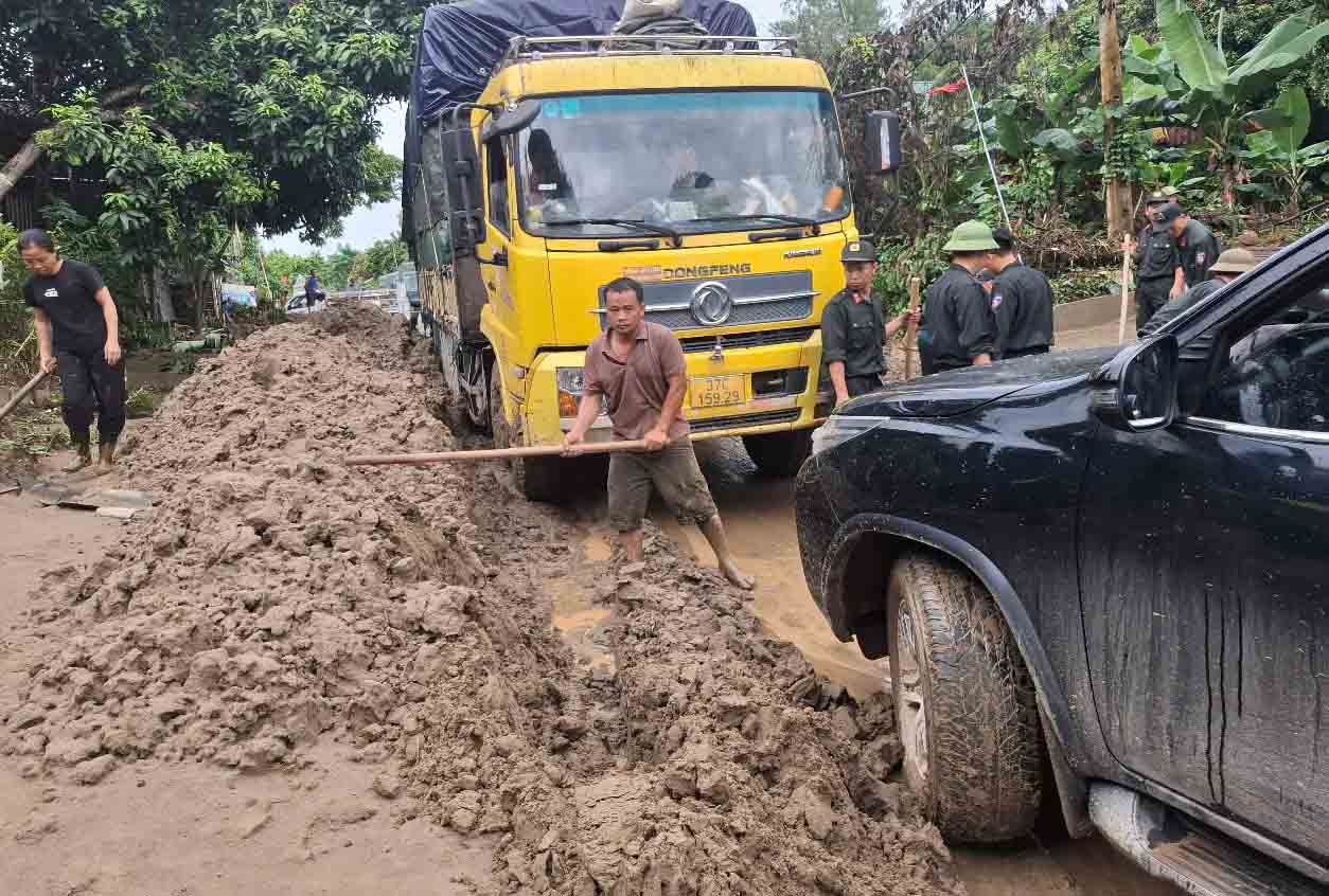 Thông tuyến tạm nhưng bùn đất hai bên Quốc lộ 7 vẫn còn rất nhiều, công việc dọn sạch hết cũng còn rất gian nan. Ảnh: Trần Tuấn.