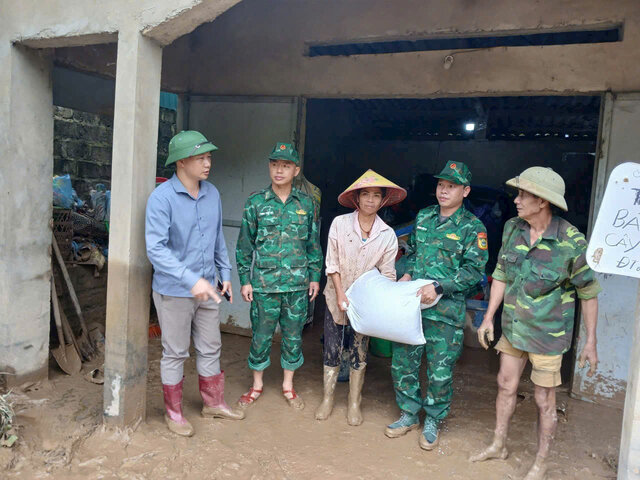 Cán bộ, chiến sĩ Đồn Biên phòng Mường Lèo gùi từng bao lương thực, chia sẻ động viên đồng bào vùng lũ. Ảnh: Yên San