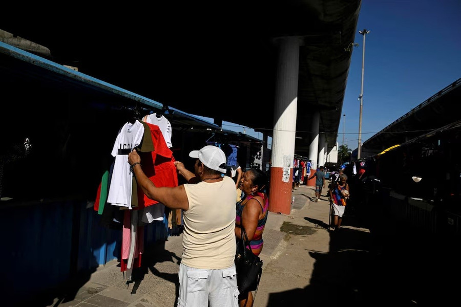 Một người đàn ông đang kiểm tra quần áo tại một khu chợ công cộng ở Havana, Cuba, ngày 22/7. Ảnh: REUTERS cuba-khu-vuc-tu-nhan-lan-dau-vuot-nha-nuoc-ve-ban-le-3.jpg