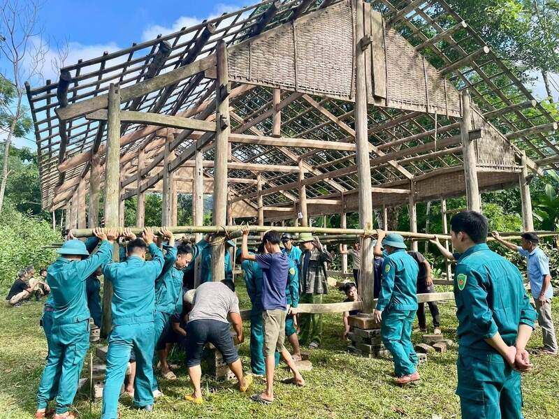 Lực lượng Công an, dân quân tự vệ và người dân hỗ trợ gia đình dựng nhà tạm ở vị trí an toàn hơn. Ảnh: Lê Phương