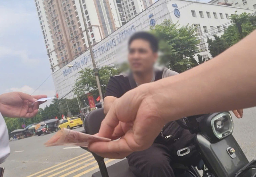 Nhân viên (áo đen) thu tiền gửi xe từ khách - (Ảnh: cắt từ video). z6975594749046-a1d384178a5da5ea89c7ce73a8142970.jpg