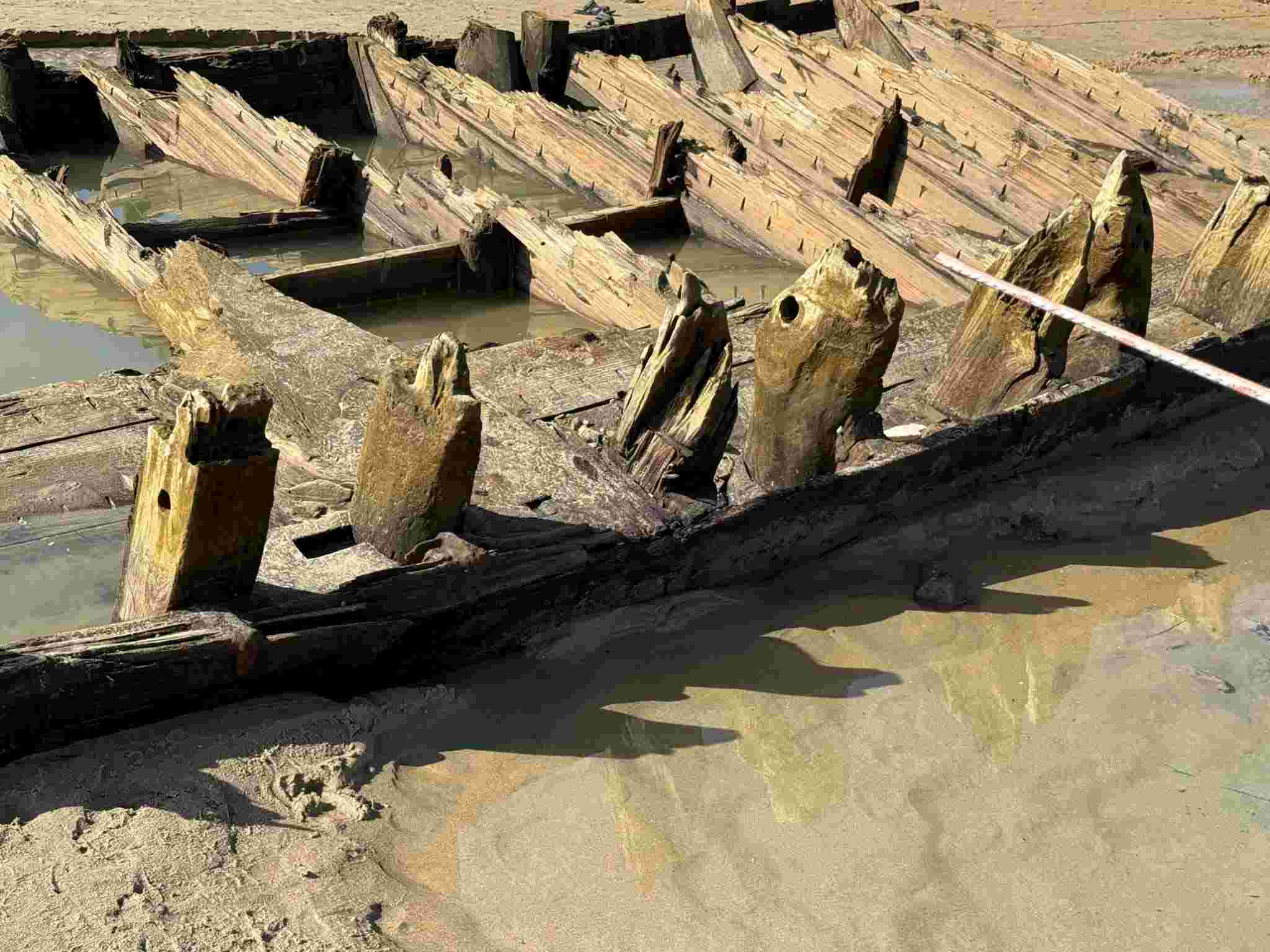 Xác tàu cổ ở Hội An đang bị cát tái vùi lấp sau khi sóng biển “phát lộ” lần thứ 2. Ảnh: Quý Dũng