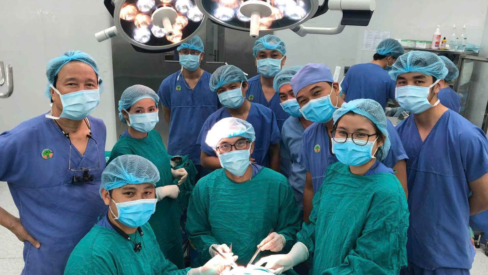 Bác sĩ Trần Thanh Trí (ngồi giữa mặc áo xanh lam) thực hiện phẫu thuật cho bệnh nhi. Ảnh: Bác sĩ cung cấp