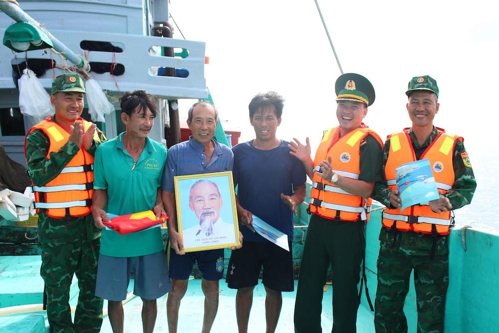Các ngư dân trên vùng biển Phú Quốc nhận ảnh Bác, cờ đỏ sao vàng sau khi được lực lượng Trạm Biên phòng Cửa khẩu Cảng Dương Đông tuyên truyền chống khai thác IUU. Ảnh: Lục Tùng.