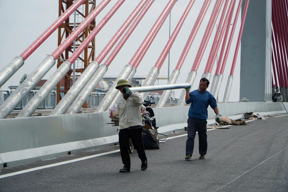 Các công nhân tiến hành thi công trên cầu vượt đường sắt. Ảnh: Quách Du