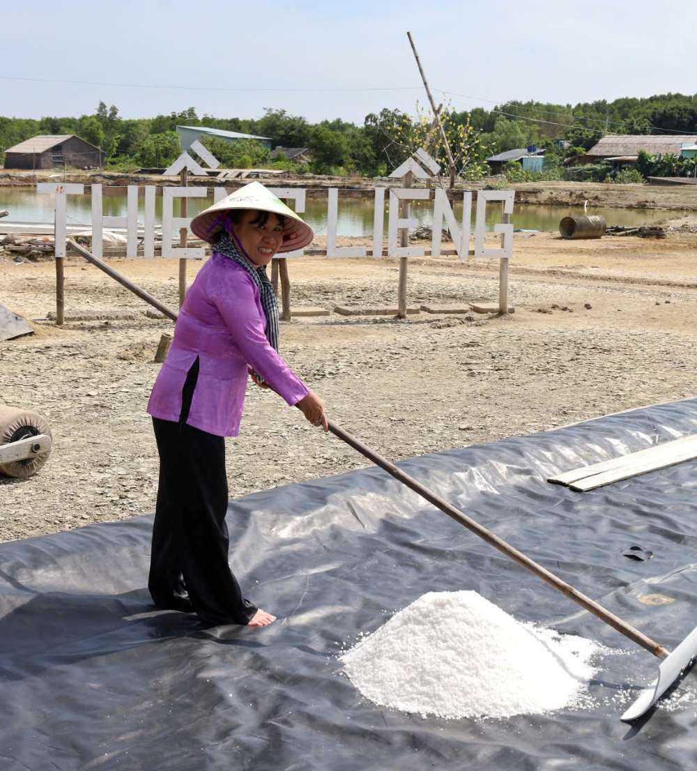 Du khách hào hứng xắn quần lội ruộng, tự tay cầm cào thu hoạch để thấu hiểu hơn về sự vất vả và giá trị của hạt muối Thiềng Liềng. Ảnh: Thái Bảo