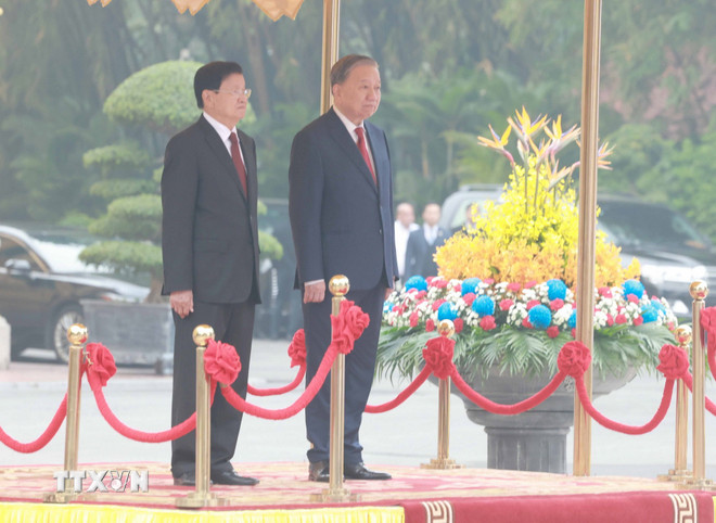 Tổng Bí thư Tô Lâm và Tổng Bí thư, Chủ tịch nước Lào Thongloun Sisoulith trên bục danh dự, thực hiện nghi thức chào cờ. Ảnh: TTXVN