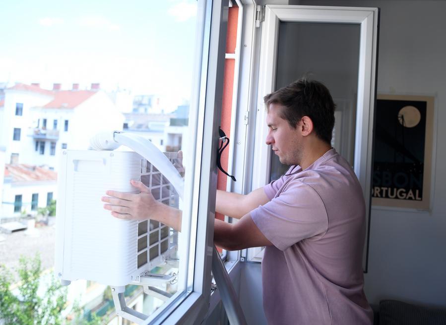 Người dân Áo Denis Yurchak lắp đặt điều hòa Midea Portasplit tại căn hộ ở thủ đô Vienna ngày 4.7.2026, trong bối cảnh châu Âu trải qua mùa hè nắng nóng cực đoan. Ảnh: Xinhua