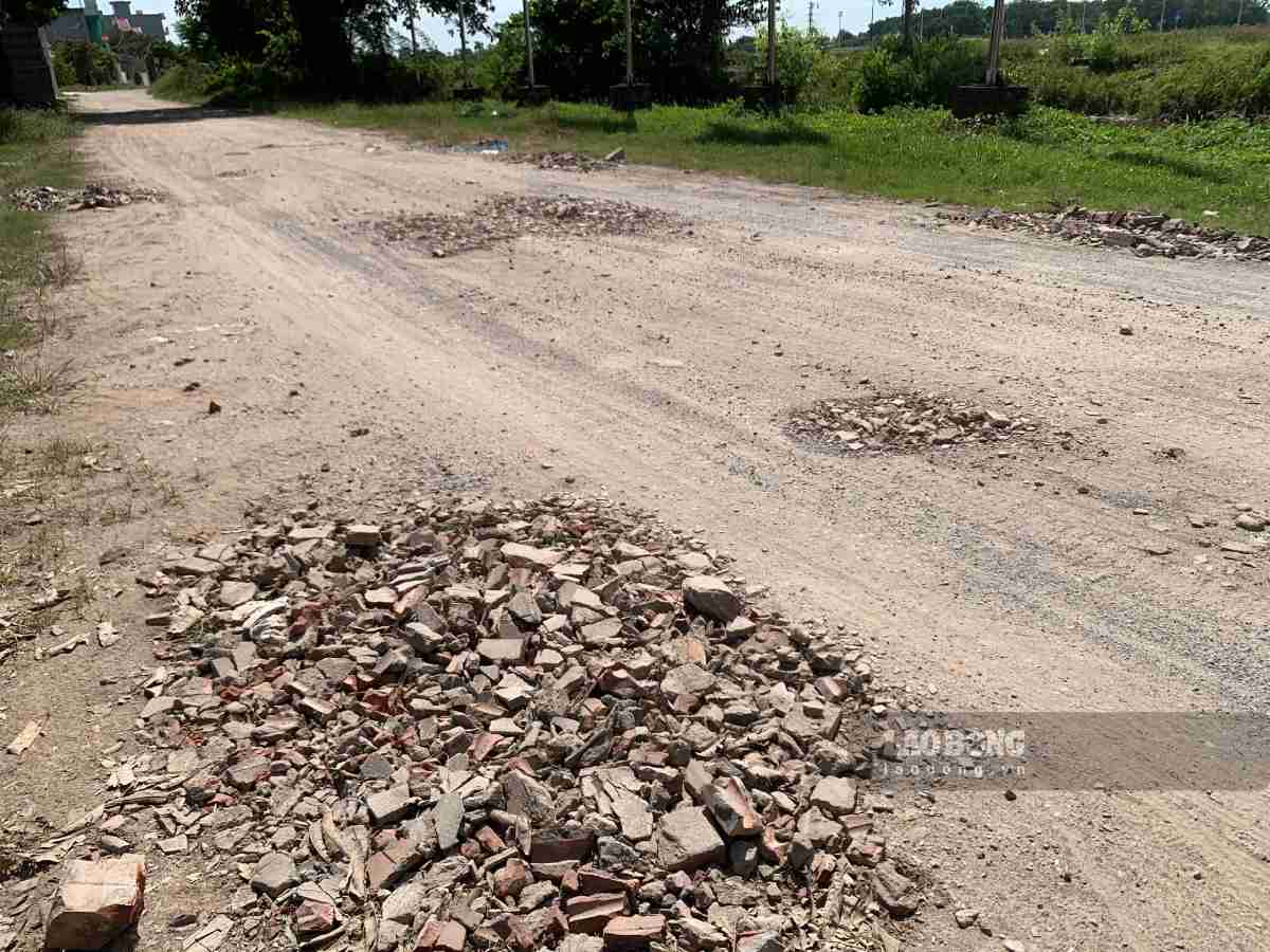 Người dân tận dụng đá, gạch vỡ để lấp vào ổ voi, ổ gà. Ảnh: Lương Hà