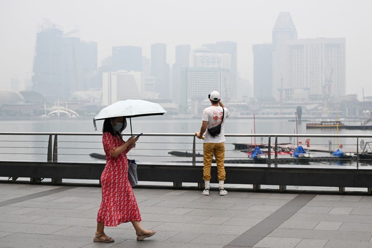 Người dân đeo khẩu trang đi bộ tại khu vực Marina Bay (Singapore) khi khói mù từ các đám cháy rừng ở Indonesia bao phủ thành phố, gây ô nhiễm không khí, ngày 12.10.2026. Ảnh: AFP